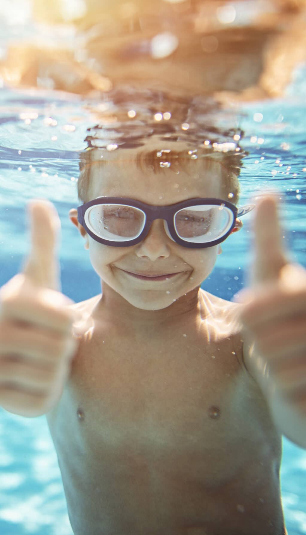 Little boy in pool showing thumbs up