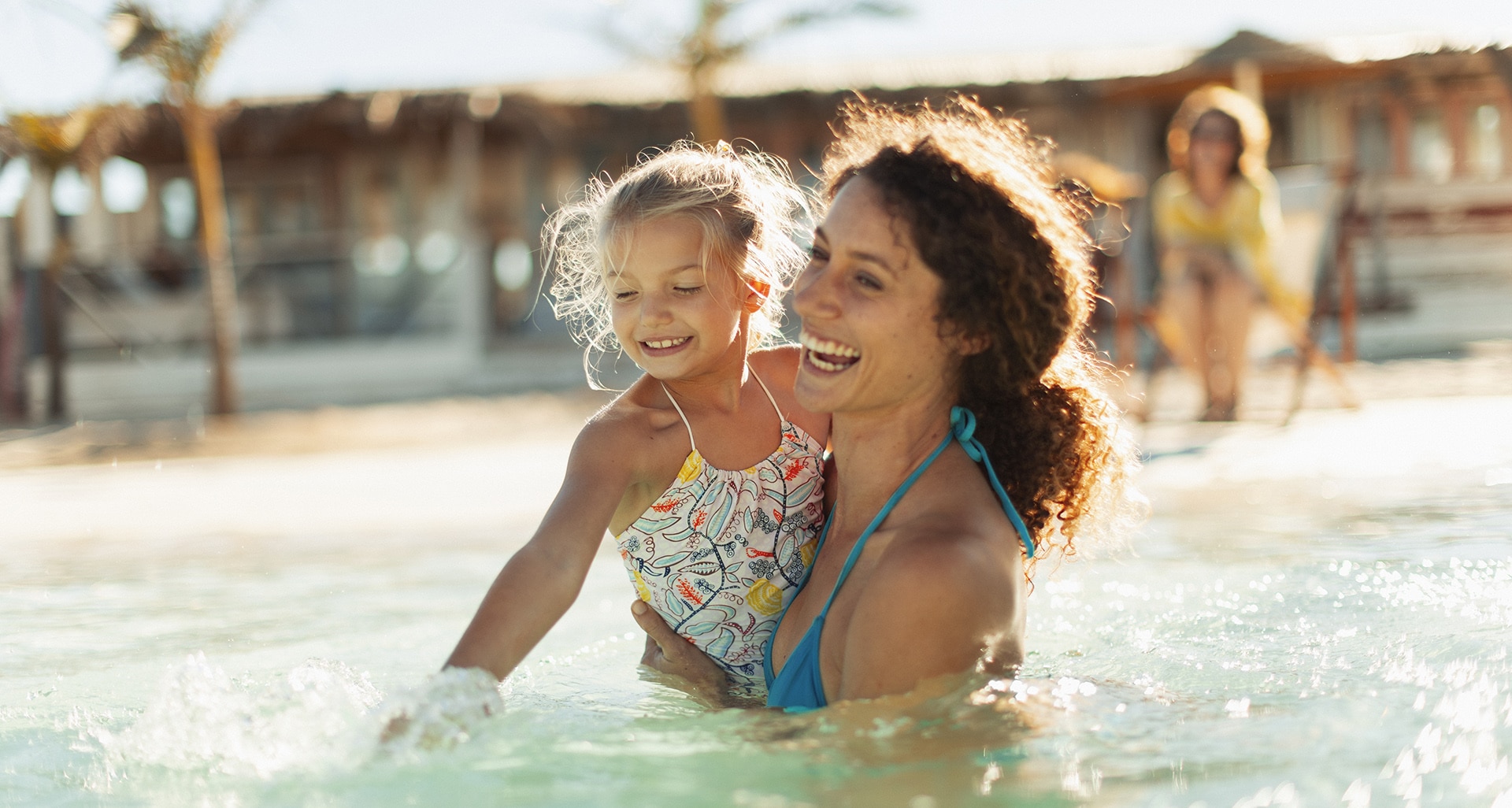 Happy mother and daughter swimming in sunny ocean